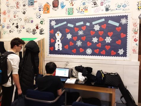 Two Uni students sitting next to snowflake-covered bulletin board