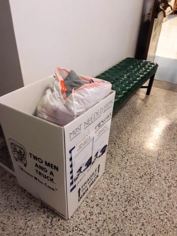 A cardboard box full of clothing sits on the second floor hallway